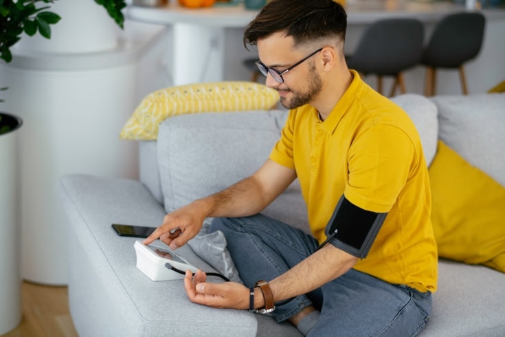 Man on couch taking blood pressure reading